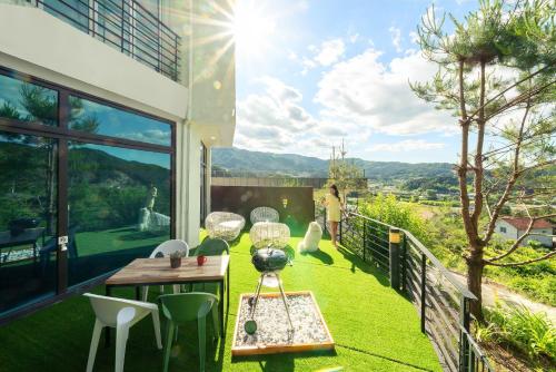 a balcony with green grass and a table and chairs at Gapyeong Bobo Dog Pool Villa in Gapyeong