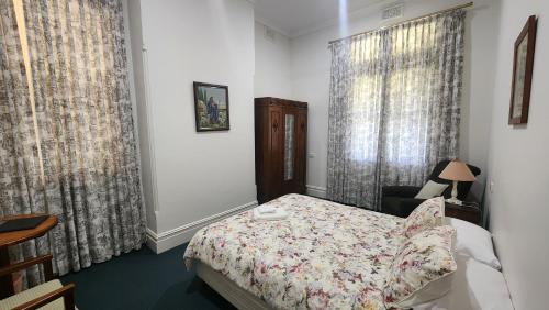 a bedroom with a bed and a chair and curtains at Mary MacKillop Spirituality Centre Central Coast in Kincumber South