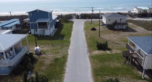 a person walking down a road next to a beach at A Drunken Parrots Beach Side Paradise in North Topsail Beach