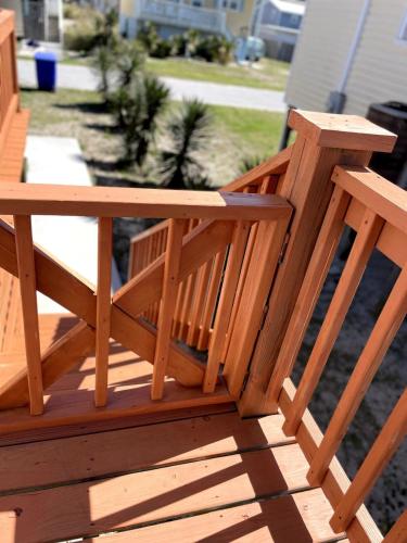 a wooden bench sitting on top of a deck at A Drunken Parrots Beach Side Paradise in North Topsail Beach