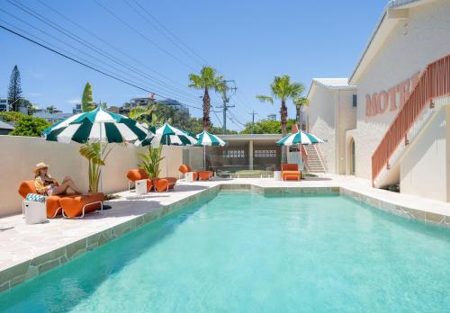 a pool with chairs and umbrellas next to a building at The Shores Miami in Gold Coast