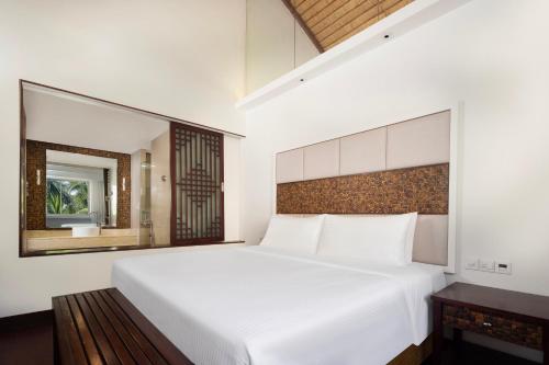 a bedroom with a large white bed and a mirror at Grand Mercure Sanya Yalong Bay in Sanya