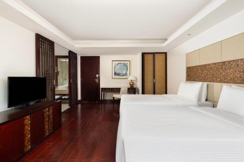 a hotel room with two beds and a flat screen tv at Grand Mercure Sanya Yalong Bay in Sanya