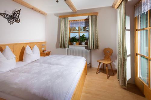 Un dormitorio con una gran cama blanca y una silla. en Braunlehen Walch, en Berchtesgaden