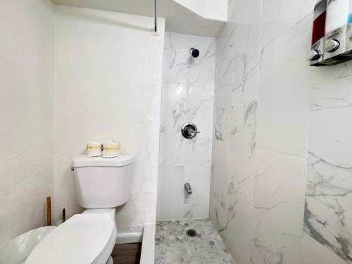 a white bathroom with a toilet and a shower at Waikiki Canal Family Room 6person in Honolulu