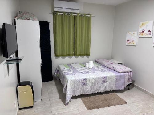 a bedroom with a bed and a green curtain at Residência Naiote in Japaratinga