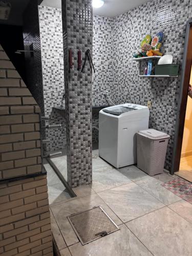 a bathroom with a toilet and a brick wall at Residência Naiote in Japaratinga