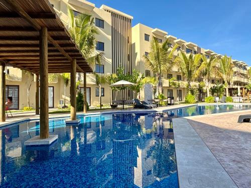 a swimming pool in front of a building with palm trees at Fantástico Depa en Cerritos OCEANNA frente al MAR ! - 237 AB - in Mazatlán