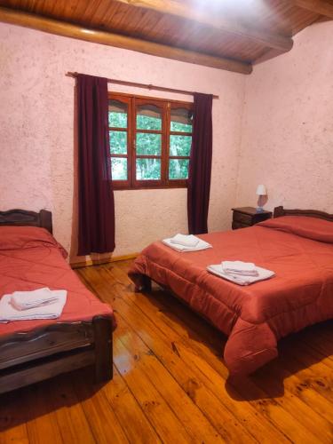 a bedroom with two beds and a window and wooden floors at Cabañas El Rosedal in San Rafael
