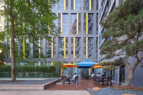 a courtyard with tables and umbrellas in front of a building at Shanghai T Plus Hotel Residence in Shanghai