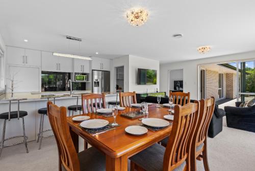 a kitchen and living room with a wooden table and chairs at The Lakeside - Tauranga Holiday Home in Tauranga