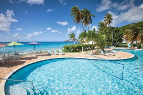 a large swimming pool with palm trees and the ocean at St Thomas Luxury Beach Resort in Nazareth