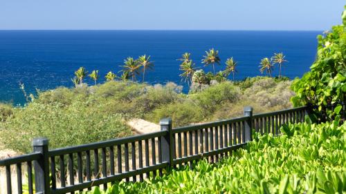 a fence on a hill with the ocean in the background at ❤PiH❤ Ikena Nani Ocean Coastline Views Mauna Kea Resort in Waimea