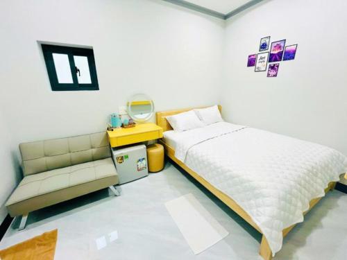 a bedroom with a bed and a couch and a mirror at Lộc Vừng Homestay in Phan Thiet