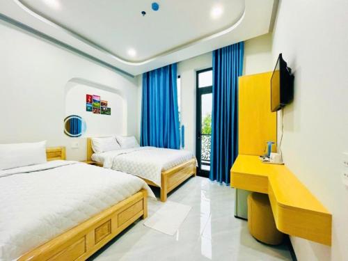 a hotel room with two beds and a television at Lộc Vừng Homestay in Phan Thiet