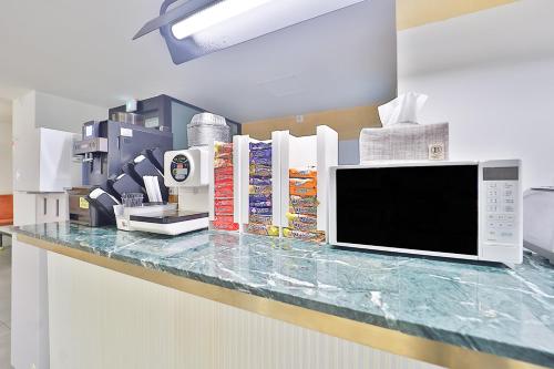 a kitchen counter with a microwave and books on it at Brown Dot Hotel Ulsan Samsan in Ulsan