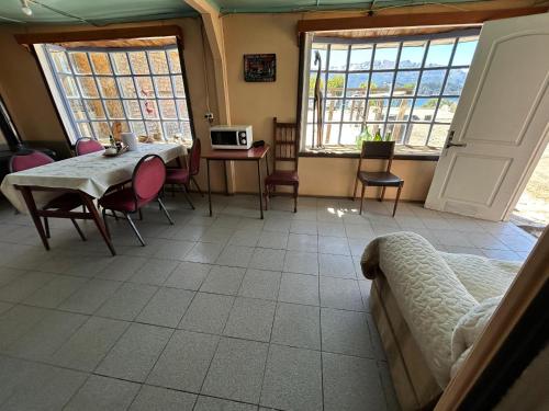 Una sala de estar con mesa y sillas y ventanas. en Hostel Las Parvas by Samtours, en Puerto Tranquilo