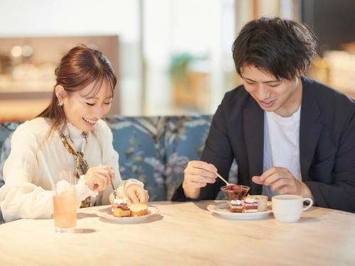 a man and woman sitting at a table eating food at Kansai Airport Washington Hotel in Izumi-Sano