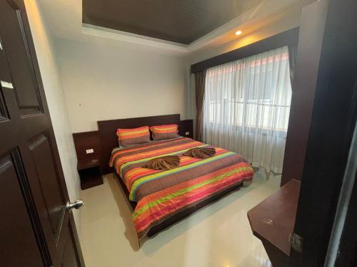 a bedroom with a bed with a colorful blanket and a window at Modern 2-Bedroom Villas with Pool Access in Krabi town