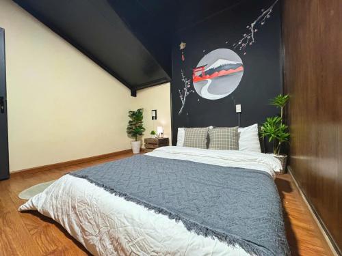 a bedroom with a large bed with a painting on the wall at SAKURA House ĐÀ LẠT in Da Lat