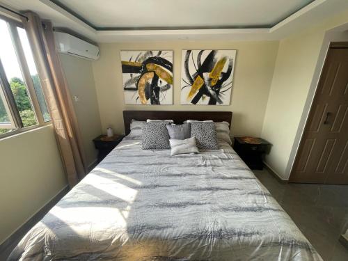 a large bed in a room with paintings on the wall at Modern Kingston Apartment Suite With Pool & Ocean View in Kingston