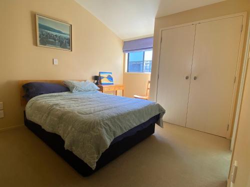 a bedroom with a bed and a cabinet and a window at Beach Break in Mount Maunganui