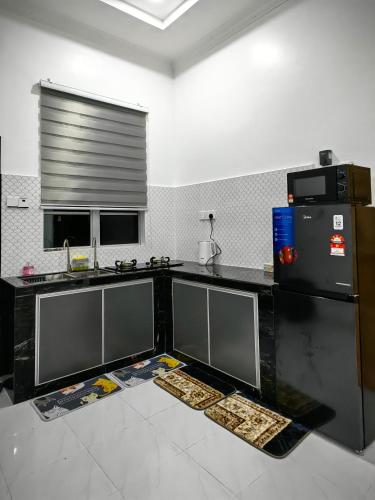 Kampong Tok PakirにあるChempaka Suite Homestayのキッチン(黒いカウンター、冷蔵庫付)