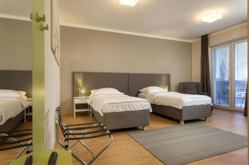 een slaapkamer met 2 bedden en een stoel. bij Apartmány Abacie in Nový Jičín