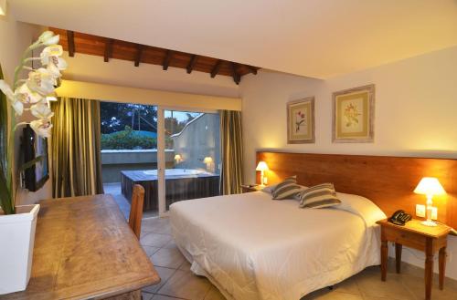 a bedroom with a bed and a table and a window at Pousada Dos Búzios in Búzios