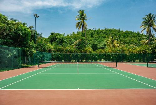 a tennis court with a net and palm trees at El Careyes Club & Residences in Careyes