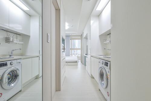 a white laundry room with a sink and washing machines at Landmark Stay in Songdo in Incheon