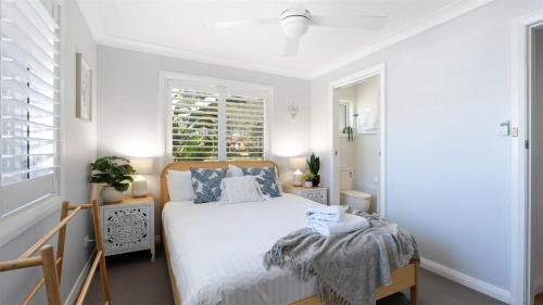 ein weißes Schlafzimmer mit einem Bett und einem Fenster in der Unterkunft Coastal Palms in Culburra Beach