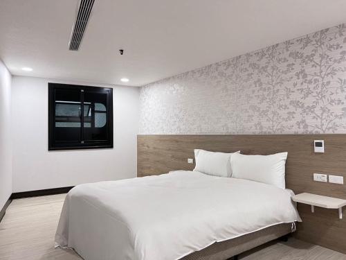 a bedroom with a large white bed and a window at 嘉樂行旅Gala Inn in Tainan