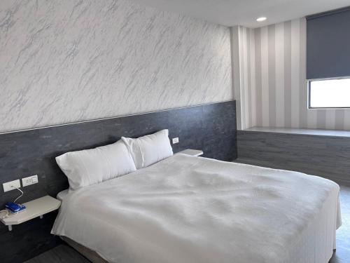a bedroom with a large white bed and a wall at 嘉樂行旅Gala Inn in Tainan