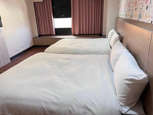 two beds in a room with white sheets and pillows at 嘉樂行旅Gala Inn in Tainan