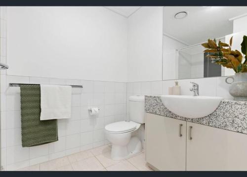 a white bathroom with a toilet and a sink at Jolimont Gem - East Melbourne Private Apt - MCG & Rod Laver Arena in Melbourne