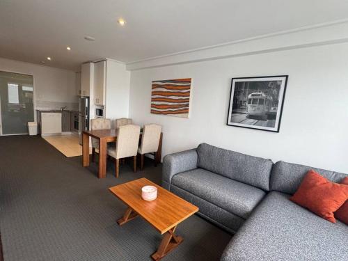 a living room with a couch and a table at Jolimont Gem - East Melbourne Private Apt - MCG & Rod Laver Arena in Melbourne