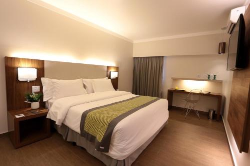 Habitación de hotel con cama grande y escritorio. en Oasis Plaza Hotel, en Ribeirão Preto