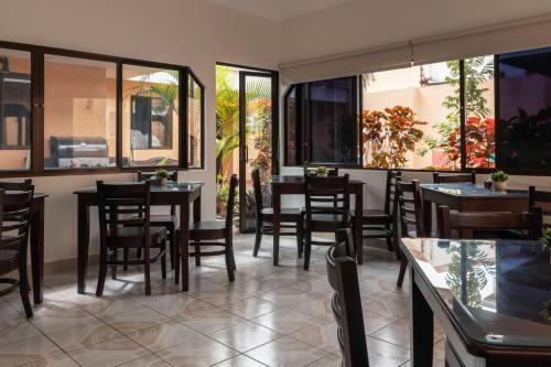 a restaurant with tables and chairs and windows at Brisas del Aeropuerto in Heredia