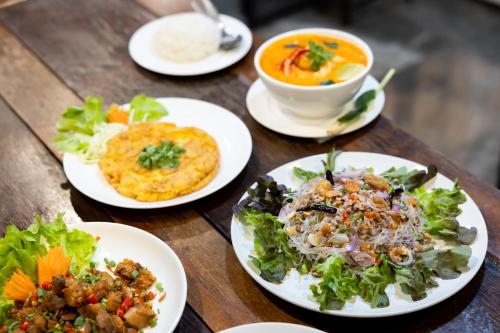 a table with plates of food and a bowl of soup at Nature Boutique Residence in Bangkok