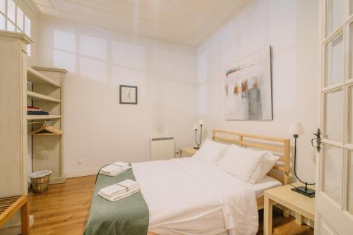 een witte slaapkamer met een bed en een boekenplank bij Camoes Deluxe Bairro Alto in Lissabon