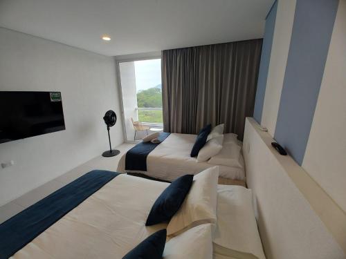 a hotel room with two beds and a flat screen tv at Santa Marta - Porto Horizonte in Santa Marta