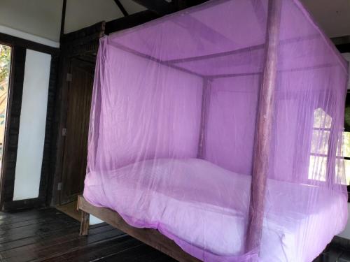 a bed covered in purple mosquito nets in a room at Shamballa Dok krai in Ban Chak Man Thet