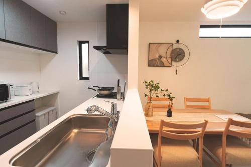a kitchen with a sink and a table with chairs at Direct to Namba, Umeda ,Airport! New house!3mins to subway! in Osaka