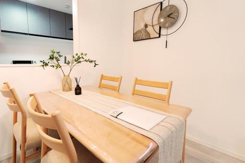 a dining room table with chairs and a clock on the wall at Direct to Namba, Umeda ,Airport! New house!3mins to subway! in Osaka