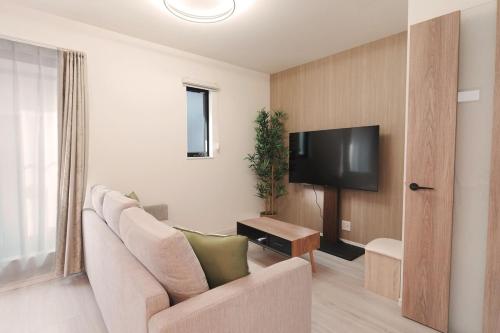 a living room with a couch and a flat screen tv at Direct to Namba, Umeda ,Airport! New house!3mins to subway! in Osaka