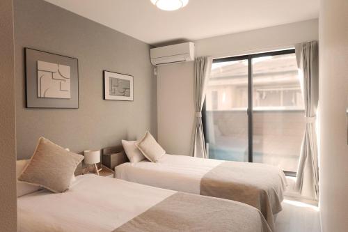 a hotel room with two beds and a window at Direct to Namba, Umeda ,Airport! New house!3mins to subway! in Osaka
