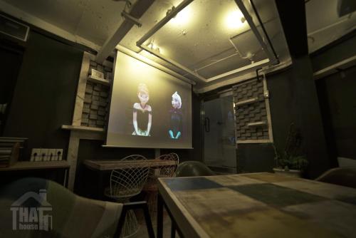a room with a screen with a table and chairs at That House Hongdae in Seoul