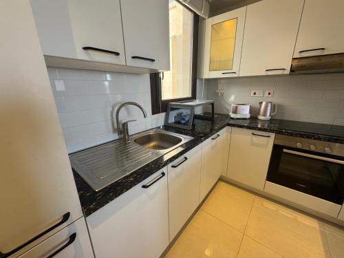 a kitchen with white cabinets and a sink at Beach house بيت البحر in As Sīfah