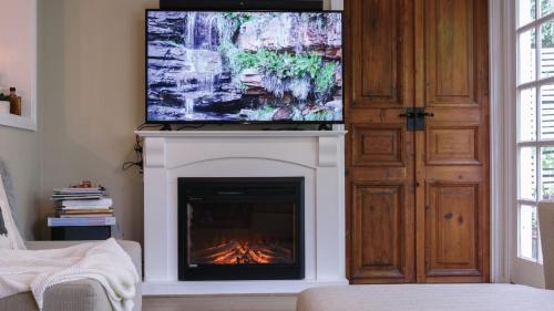 a living room with a fireplace and a flat screen tv at Frazer Place - Thoughtful Country Lodge in Daylesford